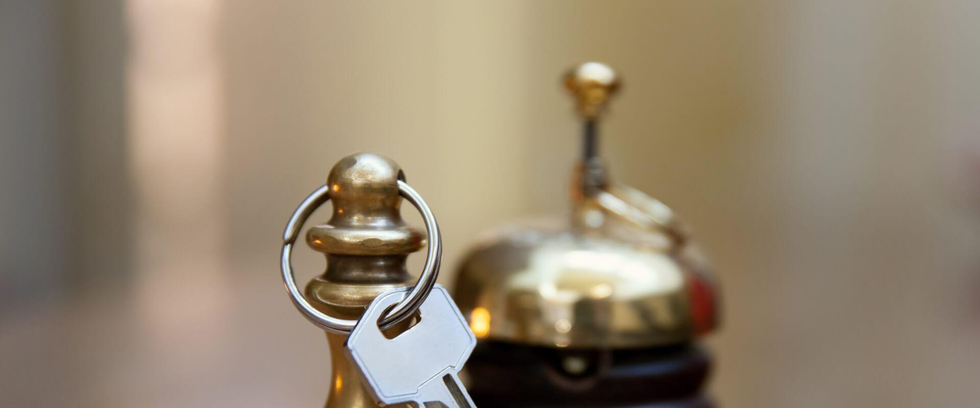 Key on pawn-shaped keychain, with bell in the background.